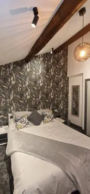 a bedroom with a bed with a wall covered in wallpaper at Weavers Cottage Whalley in Whalley