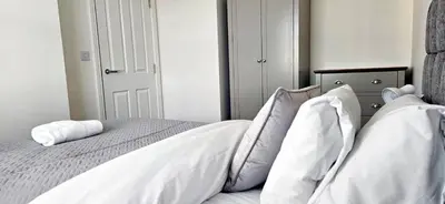 a bedroom with a bed with white sheets and pillows at House - Sleeps 11 - Parking - Station Close in Preston