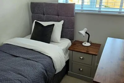 a bedroom with a bed and a nightstand with a lamp at House - Sleeps 11 - Parking - Station Close in Preston