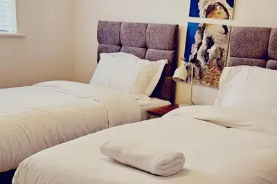 two beds in a hotel room with a pillow on the bed at House - Sleeps 11 - Parking - Station Close in Preston