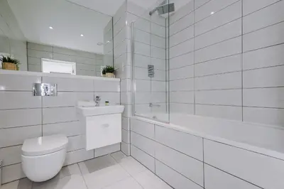 a white bathroom with a toilet and a bath tub at Flatzy - City Centre Flat With Free Parking in Liverpool