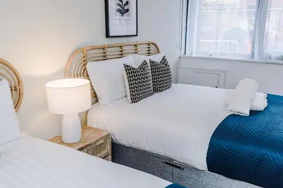 a bedroom with two beds and a lamp and a window at Flatzy - City Centre Flat With Free Parking in Liverpool