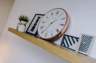 a clock sitting on top of a shelf with pictures at Flatzy - City Centre Flat With Free Parking in Liverpool