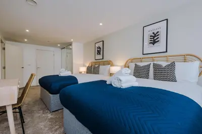 two beds in a bedroom with blue sheets and towels at Flatzy - City Centre Flat With Free Parking in Liverpool