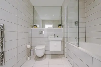 a white bathroom with a toilet and a bath tub at Flatzy - City Centre Flat With Free Parking in Liverpool