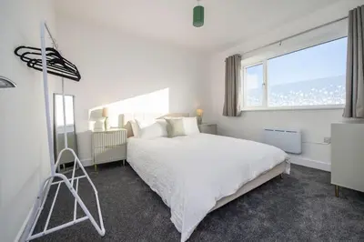 a white bedroom with a large bed and a window at Stylish 3-Bed Home-Liverpool in Liverpool