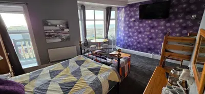 a bedroom with a bed and a purple wall at The Sands Hotel in Blackpool