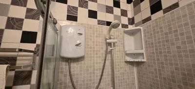 a shower in a tiled bathroom with a blow dryer at The Sands Hotel in Blackpool