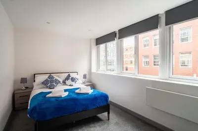 a bedroom with a bed and two windows at Convenient 1 Bedroom Apartment in Preston Centre in Preston