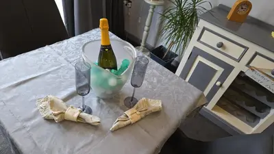a white table with a bottle of wine and glasses at Haven Lodge Kirkby In Furness, with views to the estuary and hot tub, ideal romantic break in Soutergate