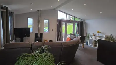 a living room with a couch and a tv at Haven Lodge Kirkby In Furness, with views to the estuary and hot tub, ideal romantic break in Soutergate