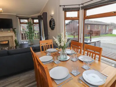a dining room with a table and chairs and a couch at Lakeside 18 in Carnforth