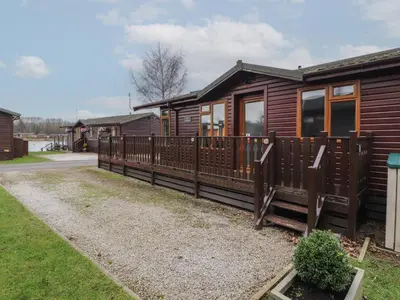 a wooden cabin with a fence in front of it at Lakeside 18 in Carnforth