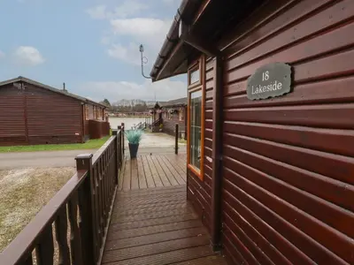 a wooden walkway next to a building with a sign on it at Lakeside 18 in Carnforth