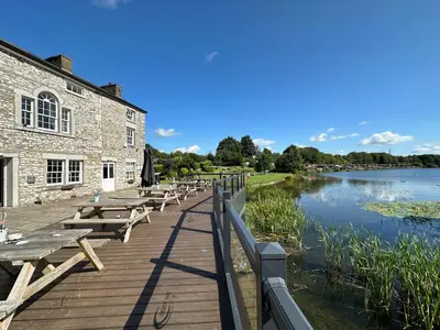 a row of picnic tables on a boardwalk next to a river at Lakeside 18 in Carnforth