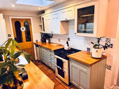 a kitchen with white cabinets and a stove top oven at Lilac Cottage in Farington