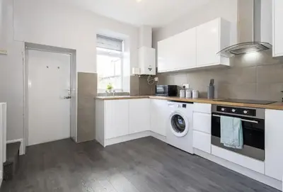 a kitchen with white cabinets and a washer at Cosy 2 Bed House for Contractors in Accrington