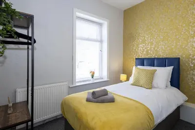 a bedroom with a bed with a blue headboard and a window at Cosy 2 Bed House for Contractors in Accrington