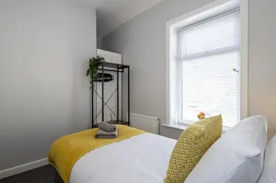 a bedroom with a bed with a yellow blanket and a window at Cosy 2 Bed House for Contractors in Accrington