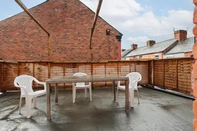 a table and chairs on a patio with a brick wall at Roof Terrace WM Smart TV Free Parking in Liverpool