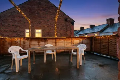 a table and chairs on a patio with lights at Roof Terrace WM Smart TV Free Parking in Liverpool