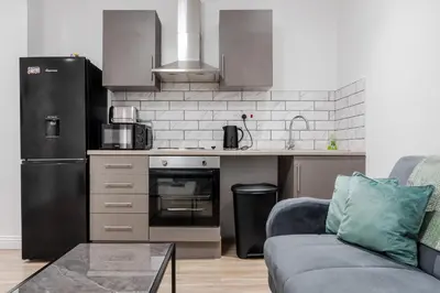 a kitchen with a black refrigerator and a couch at Roof Terrace WM Smart TV Free Parking in Liverpool