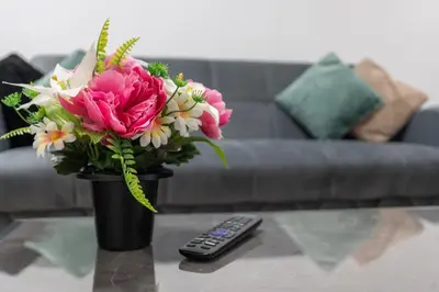 a vase of flowers on a table next to a remote control at Near LFC & City Budget LongTerm Free Parking in Liverpool