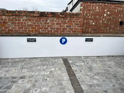 a white fence with a sign on it next to a brick wall at Olive Lodge Lytham in Lytham St Annes