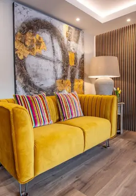 a yellow couch in a living room with a painting at Scallop Lodge Lytham in Lytham St Annes