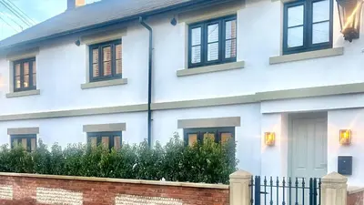 a white house with black windows and a brick fence at Scallop Lodge Lytham in Lytham St Annes