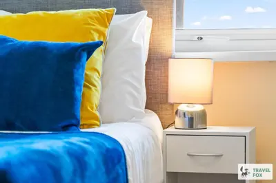 a bed with a blue and yellow pillow and a lamp at Miriam's House in Saint Helens