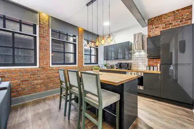 a kitchen with a table and chairs and a brick wall at Industrial 2BR Apt, Liverpool City Centre Sleeps 8 in Liverpool