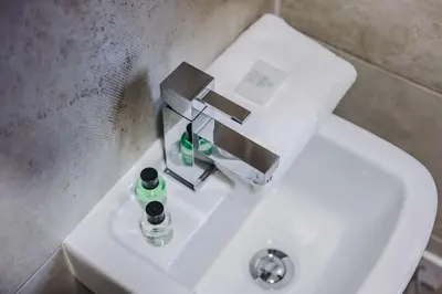 a bathroom sink with a faucet and a bottle of soap at Industrial 2BR Apt, Liverpool City Centre Sleeps 8 in Liverpool