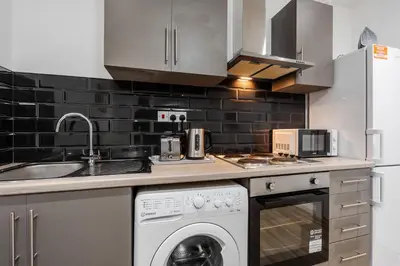 a kitchen with a washing machine and a sink at Ideal Work Trips Washer SofaBed Free Parking in Liverpool