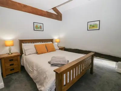 a bedroom with a large bed with two lamps and two tables at Lady Barn in Grange Over Sands