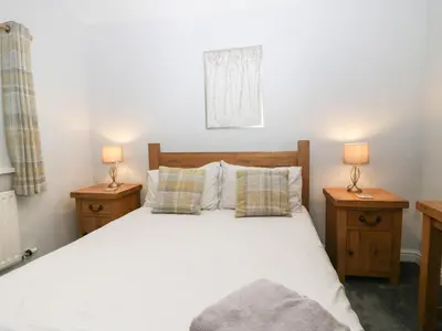 a bedroom with a white bed with two night stands at Lady Barn in Grange Over Sands