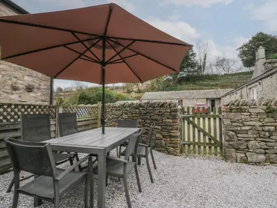 a wooden table and chairs with an umbrella at Lady Barn in Grange Over Sands