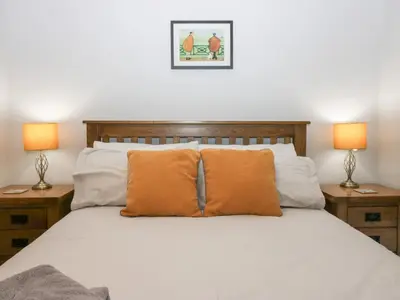 a bedroom with a bed with orange pillows and two lamps at Lady Barn in Grange Over Sands