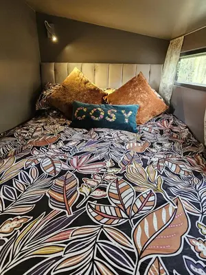 a bed with a colorful comforter and pillows on it at The Garden in Hambleton