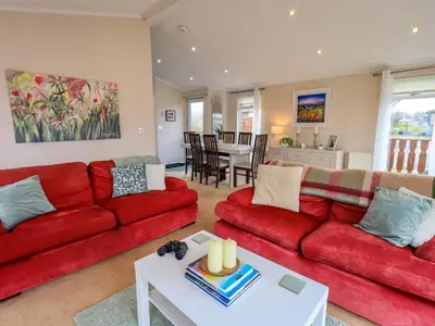a living room with red couches and a table at Otters Reach in Carnforth