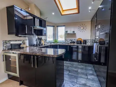 a large kitchen with black cabinets and a large island at Otters Reach in Carnforth