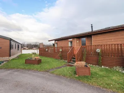 a house with a fence and some plants in a yard at Otters Reach in Carnforth