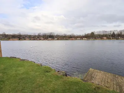 a large body of water with a wooden dock at Otters Reach in Carnforth