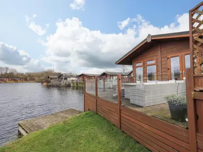 a house on a dock next to a body of water at Otters Reach in Carnforth