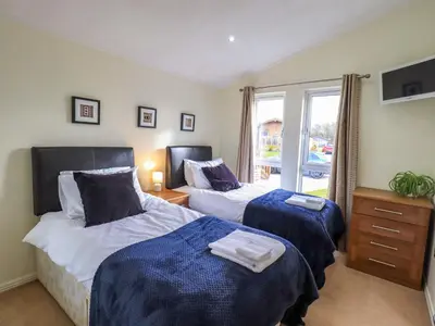 a bedroom with two beds and a window at Otters Reach in Carnforth