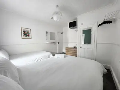 a white bedroom with two beds and a window at The Everglades in Blackpool