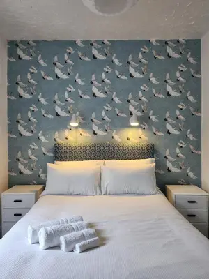 a bedroom with a large bed with birds on the wall at The Everglades in Blackpool