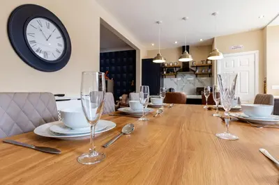a table with wine glasses and a clock on the wall at Ocean Suites HOT TUB - sleeps 11 in Blackpool