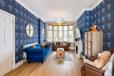 a living room with blue walls and a blue couch at Ocean Suites HOT TUB - sleeps 11 in Blackpool