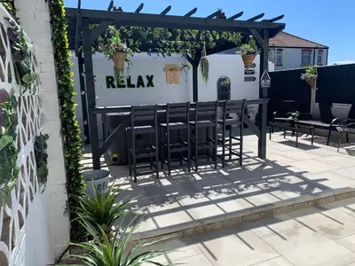a patio with benches and a pergola at Ocean Suites HOT TUB - sleeps 11 in Blackpool